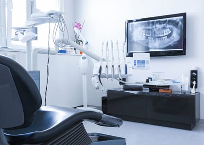 Dental chair, instruments, and an x-ray on a TV on the wall - for second opinion dentistry