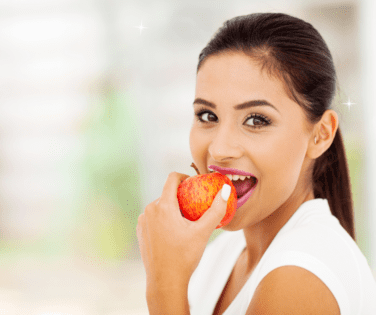 Woman Smiling and Biting Into Red Apple