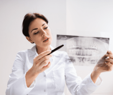 Woman Holding Dental X-Ray Pointing to Wisdom Teeth