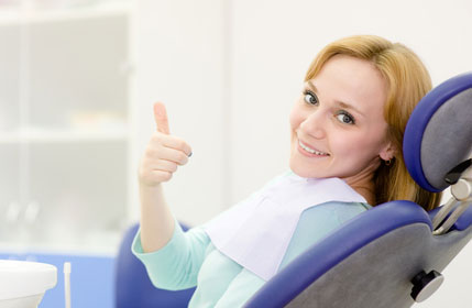 Smiling woman giving a thubs up from the dental chair