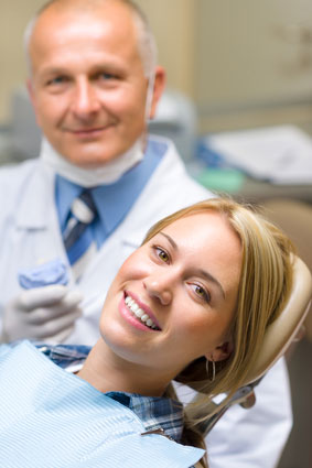 Woman in dental chair smiling with her dentist nearby