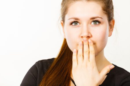 Woman covering her mouth with her hand.